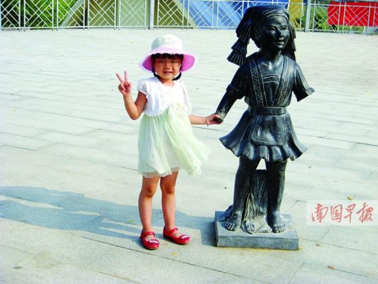 南宁市凤岭儿童公园内，一名儿童正在和一尊双臂断落的雕塑合影。南国早报记者 王春楠 摄