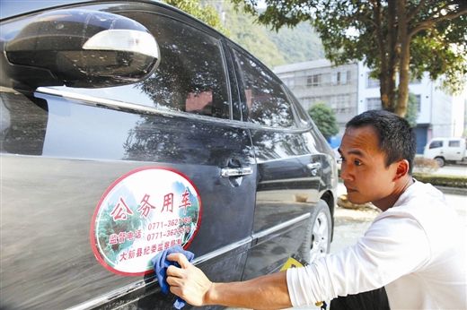 12月4日，工作人员在大新县一家政府机构的公务用车上张贴标识。