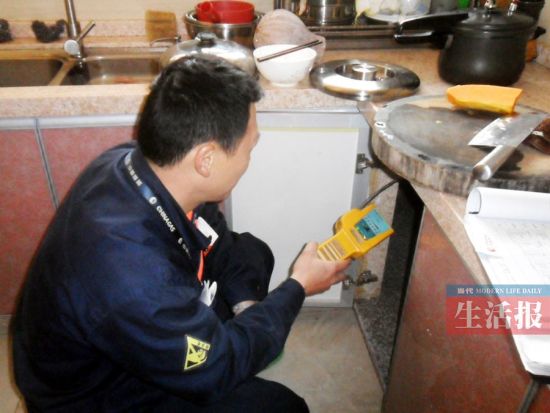 图为安检员使用可燃气体探测器为住户做微漏检查。