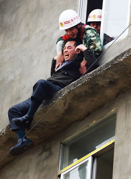消防员抓住杨某，把他拉进屋内。图片来源：南国早报