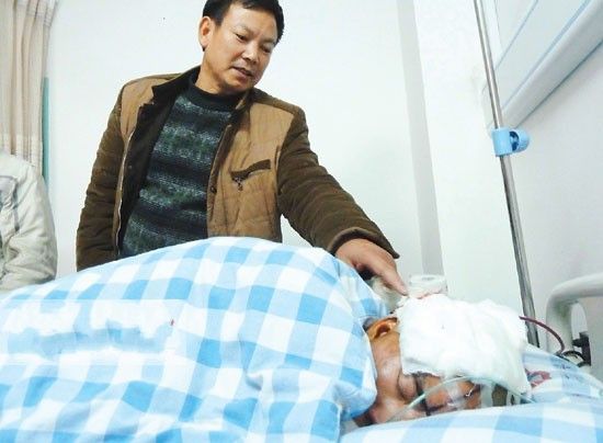 伤者经家财睡在病床上，头部右侧包裹着纱布，手术时头部被抽出60毫升淤血。记者 邓振福 摄