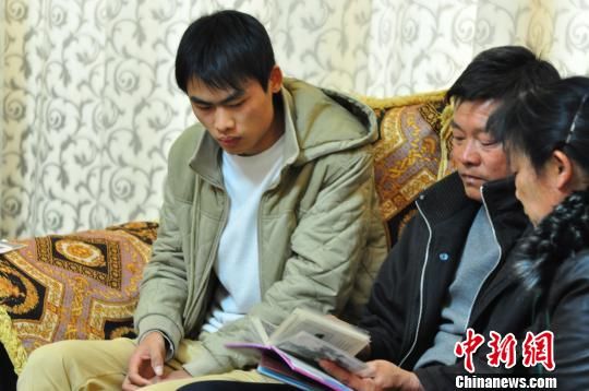 1月27日，在警方帮助下，杨迪清夫妇与黄渊源在柳州火车站贵宾候车室相见。图为杨迪清翻开儿子小时候的照片。　周潇男 摄 