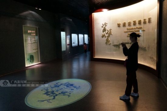 瓷器展馆中，一位市民站在投影的青花瓷绘画前拍照。广西新闻网记者 邓昶摄