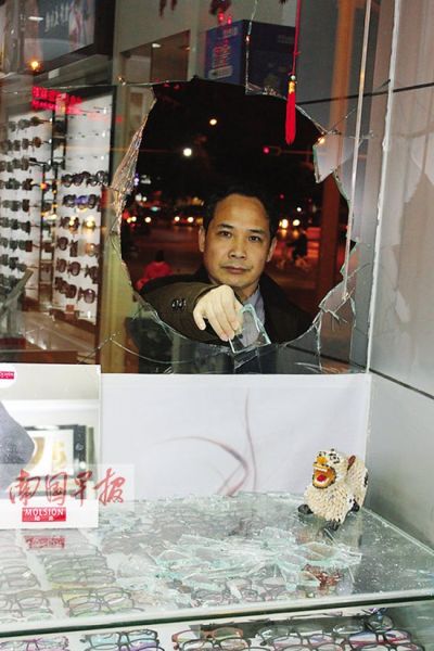 眼镜店的钢化玻璃被砸了一个大窟窿。南国早报记者 苑长军摄 