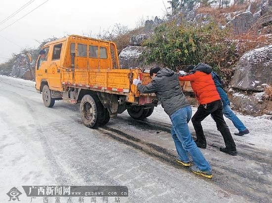 2月11日，在全州县白宝乡公路上，众人帮助打滑的汽车前行。王滋创 李宗和 摄