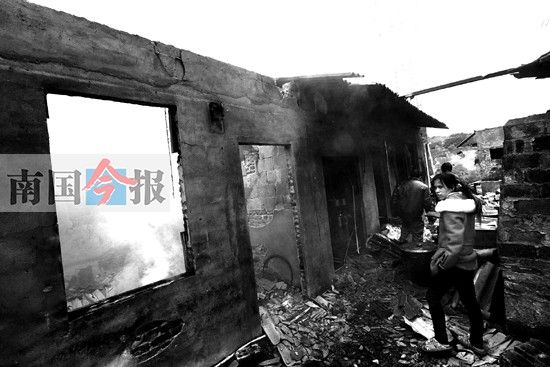 昨日下午，一名女子查看自己租住的被烧毁的房屋。记者 张存立 摄
