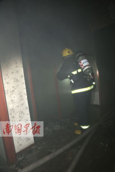 消防员在漆黑的火场中检查火情。记者 邹财麟摄