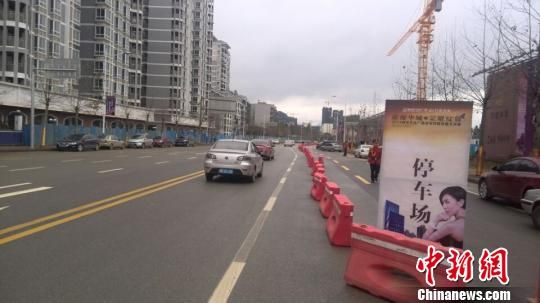 3月8日，柳州万达广场行促销宣传活动现场，附近道路被房开商用路障圈占用作停车场，延绵一公里长。蒙鸣明 摄 