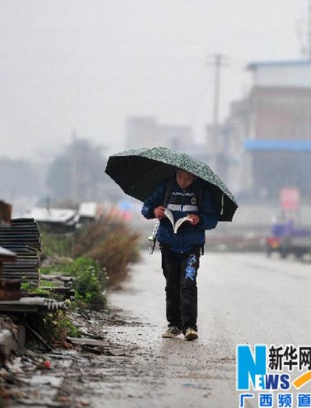 3月11日，在广西柳州市门头路，一名小学生在雨雾中放学回家。新华社记者 黄孝邦 摄