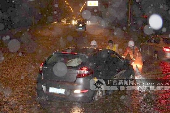 消防员将“抛锚”的小车推出积水区。图片来源：广西新闻网