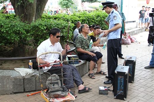 民警在朝阳广场向演奏乐器的群众发放控制噪声宣传资料